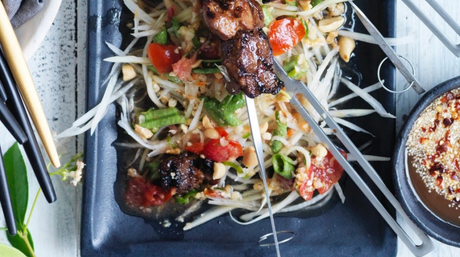 绿色木瓜沙拉用作烤猪肉串的床。