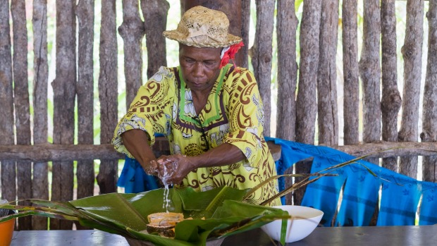 卡纳克妇女用根菜、香蕉和椰奶包着香蕉叶里的蛋白质，制作bougna。