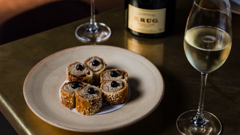 Krug Champagne与哺乳猪香肠卷在悉尼的Bennelong。“title=