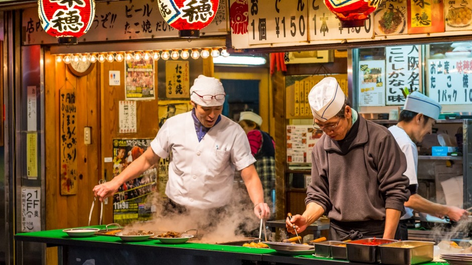 烹调takoyaki的街道食品供应商在大阪，日本。