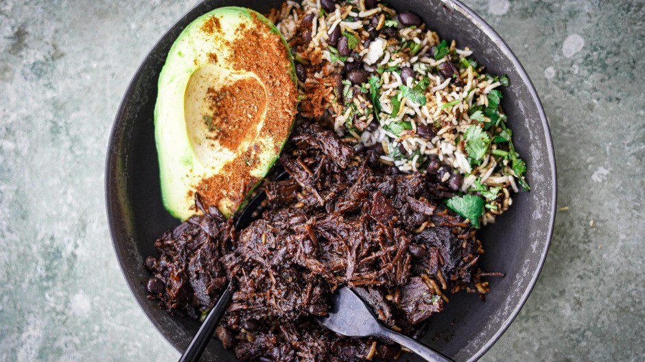 墨西哥炖牛脸配豆子，米饭和牛油果撒上一些香料。